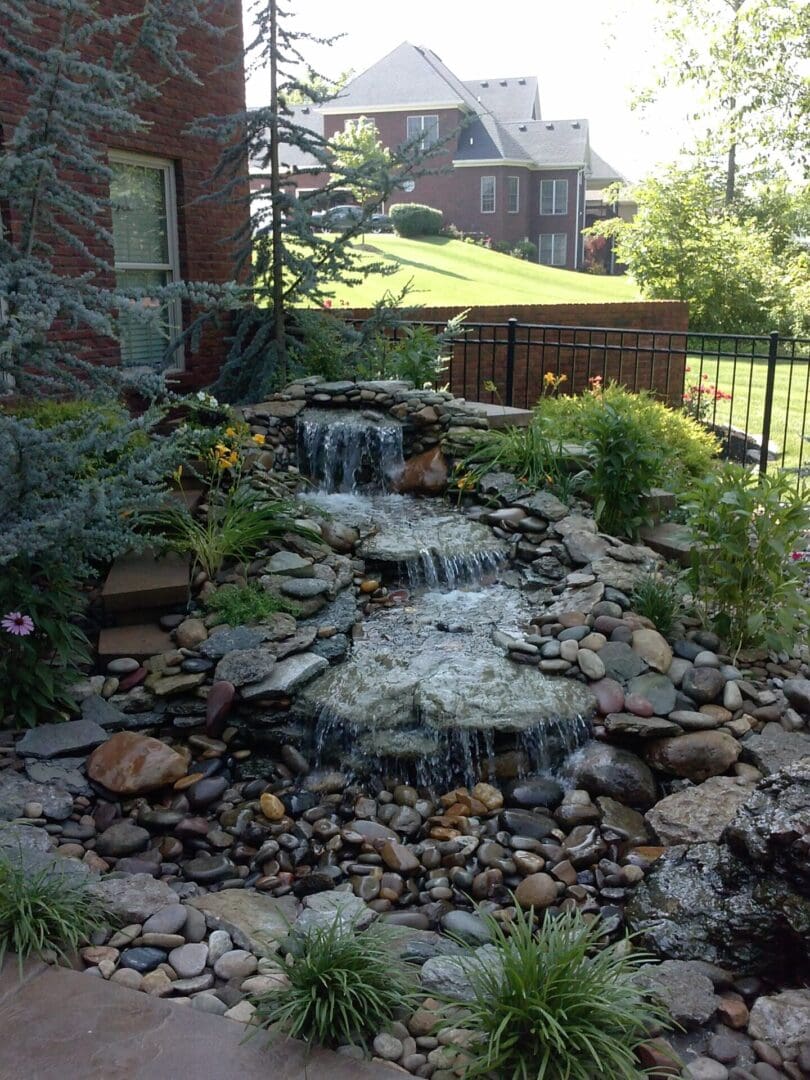 A backyard with rocks and water flowing from the top.