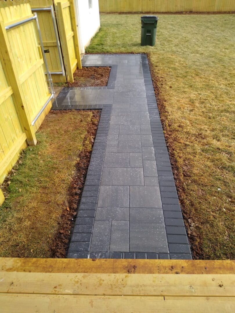 A walkway with brick and stone is in the middle of a yard.